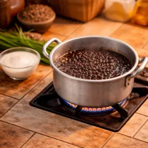 Cách Nấu Chè Đậu Đen Nước Cốt Dừa Mau Mềm, Không Sượng 1 Nồi chè đậu đen đang được ninh nhừ trên bếp ga, ăn kèm với bát nước cốt dừa béo ngậy bên cạnh.