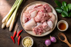 Cách Làm Gà Xào Sả Ớt Thơm Ngon, Thịt Săn Đậm Vị, Chuẩn Bếp Nhà 1 Nguyên liệu làm gà xào sả ớt gồm gà ta, sả tươi, ớt sừng, tỏi và lá chanh bày trên mặt bàn gỗ